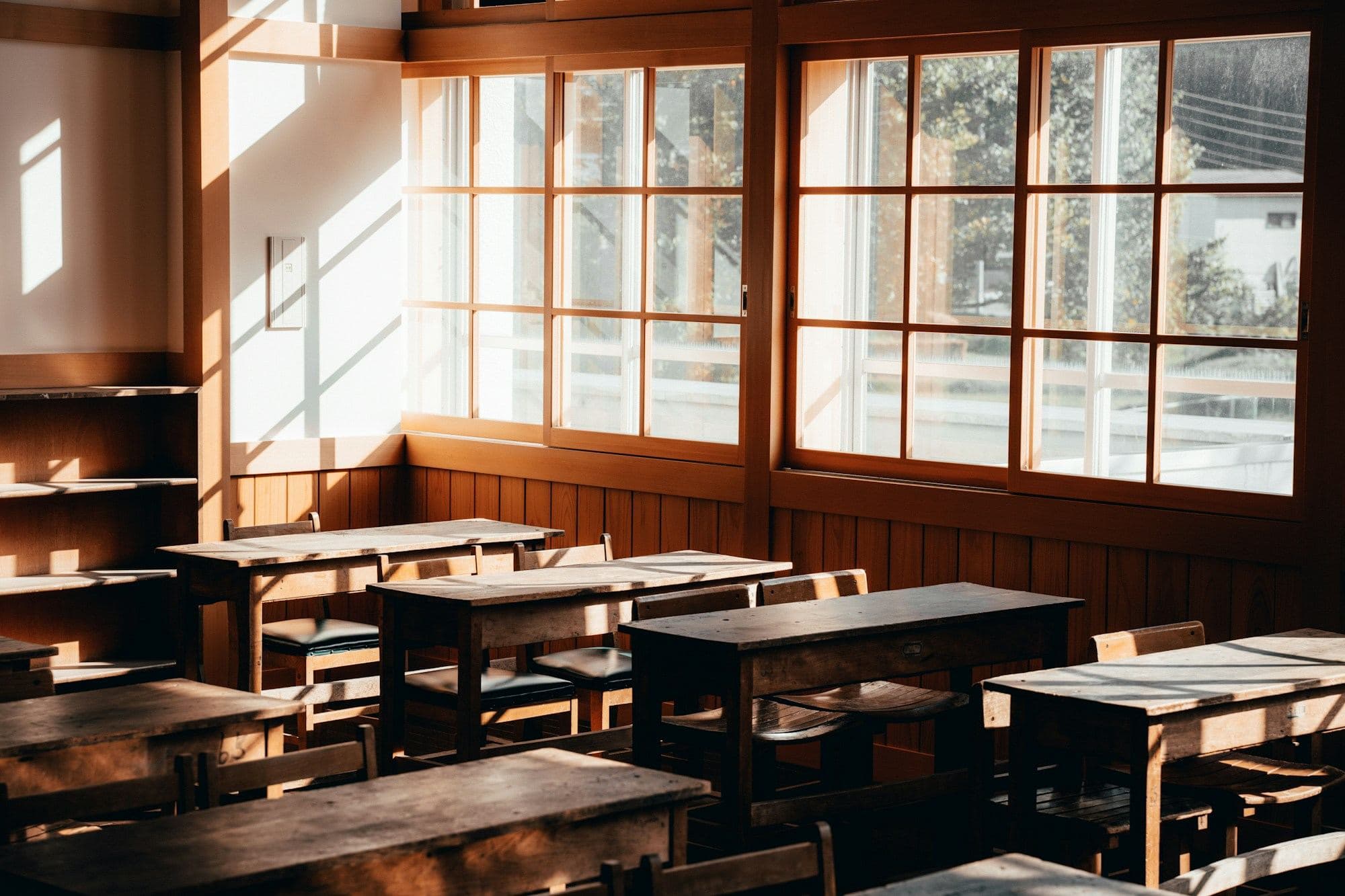 Empty classroom with wooden desks and broad windows