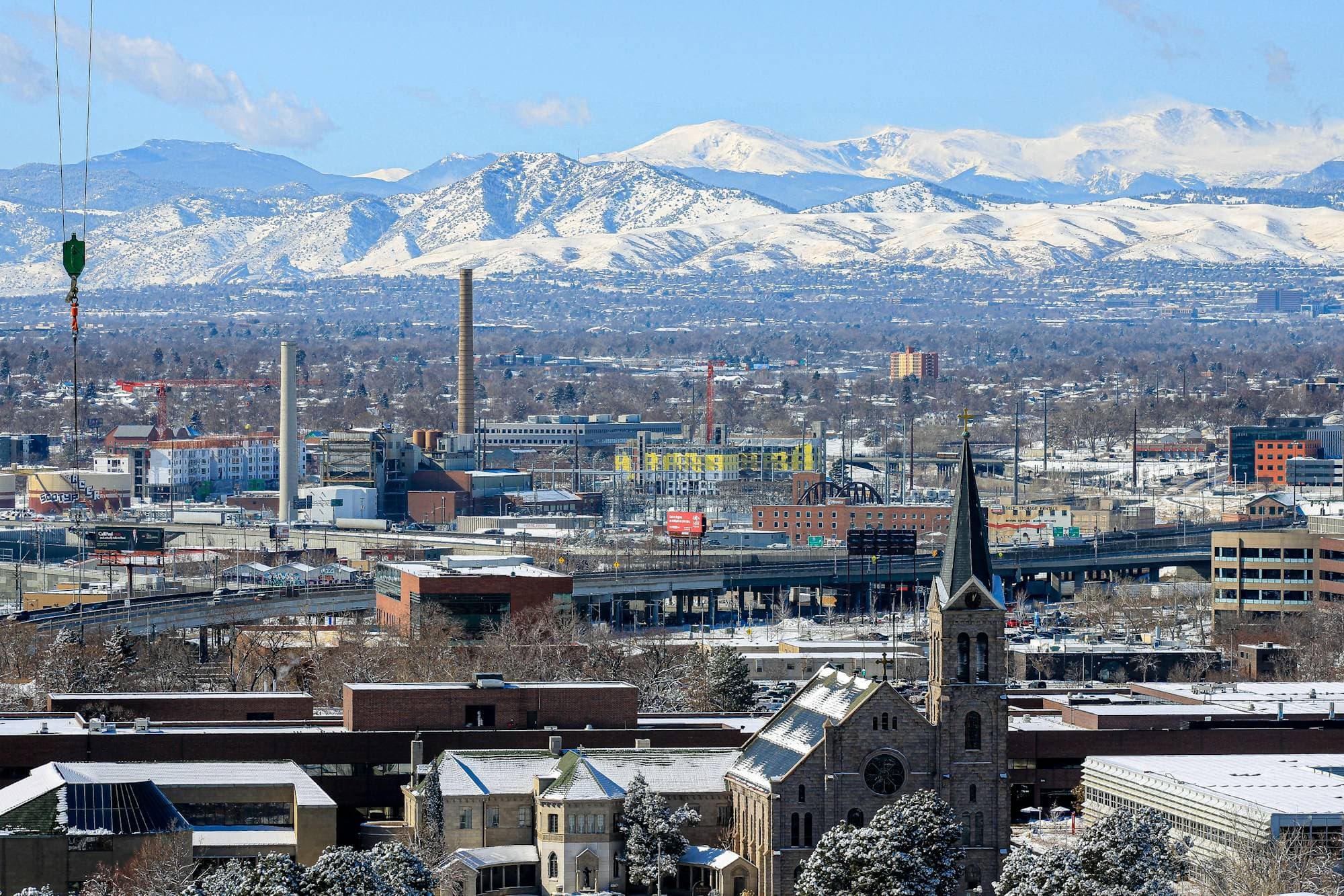 Denver buildings and a church steeple below the snow-covered Front Range