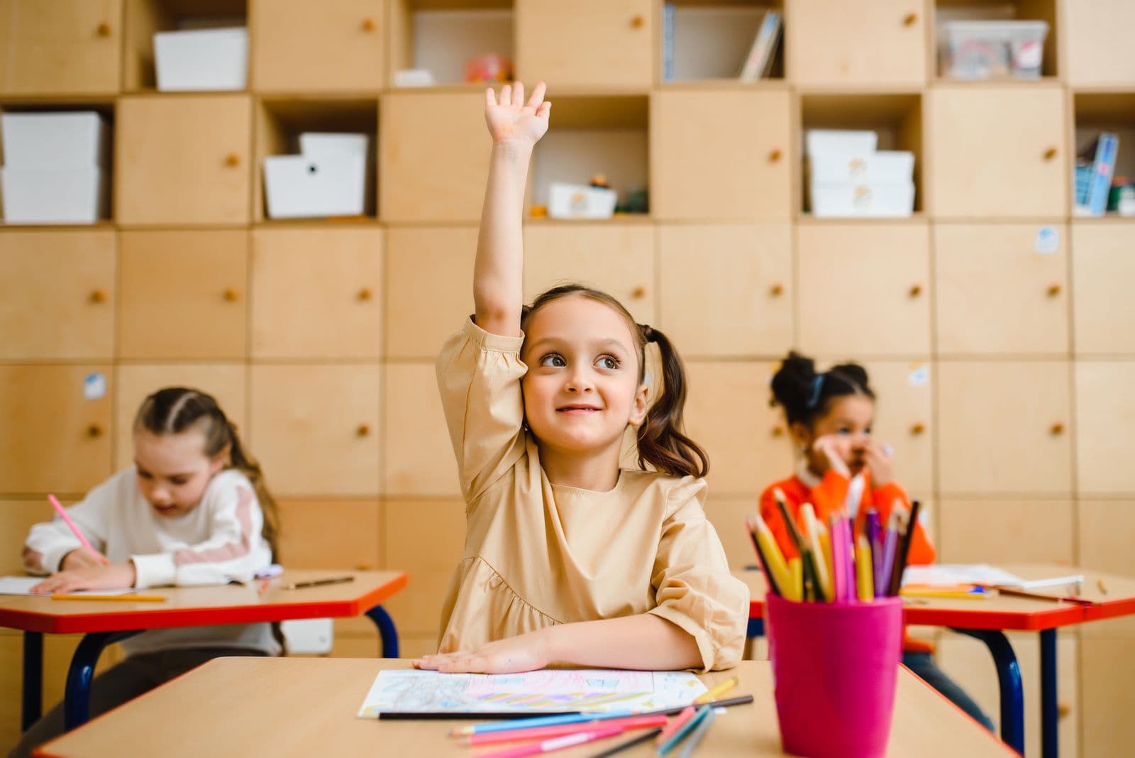 Young student raising her hand in a classroom